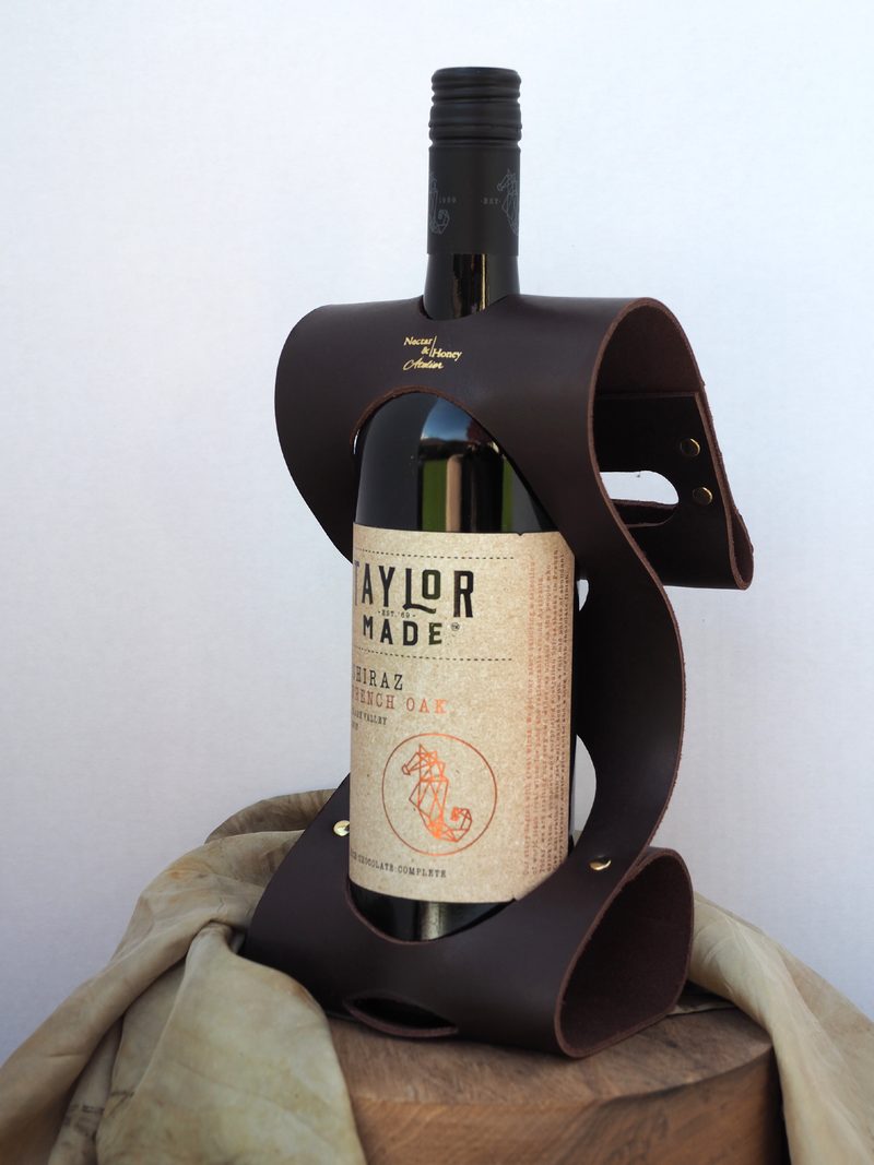 Chocolate-brown leather wine carrier holding a bottle of Taylor Made Shiraz